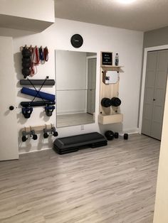 an empty room with mirrors, dumbs and exercise equipment on the floor in front of it