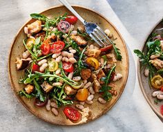 two plates filled with salad and meat on top of a table next to each other