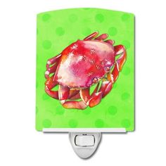 a green night light with a red crab on it's face and polka dots in the background