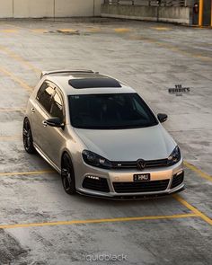 a silver car is parked in an empty parking lot with yellow lines on the ground