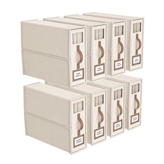 six white storage boxes with brown handles and labels on the sides, all stacked together