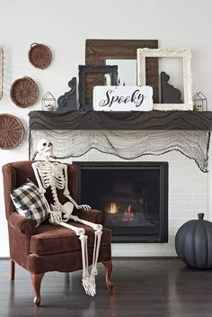 a skeleton sitting on a chair in front of a fireplace with halloween decorations around it