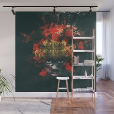 a wall mural with a woman's face and red flowers on it, in front of a bookshelf