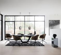 a modern dining room with large windows and chairs