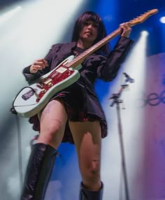 a woman in short shorts and boots holding a guitar