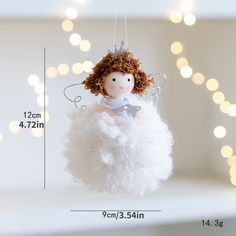 a white angel ornament hanging from a string with lights in the back ground