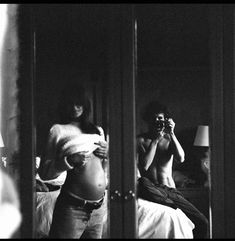 a man taking a photo of himself in the mirror with his cell phone while pregnant