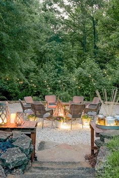 a fire pit surrounded by chairs and lights in the middle of a wooded area with lots of trees