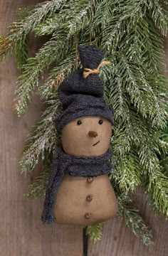 The Stiffened Fabric Primitive Snowman Ornament is a decorative plush snowman figurine made of grungy, stiffened ivory fabric. The snowman has a carrot nose, jingle bell buttons, and wears a matching blue fabric hat and scarf. The top of the ornament includes a jute string hanger to use for display, bringing a rustic and primitive touch to a Christmas tree during the holiday season. Measures 5.5” high by 2.75” wide by 1.5” deep. Free Primitive Patterns, Primitive Christmas Ornaments, Primitive Ornaments, Fabric Christmas Decorations, Primitive Fall Decor, Primitive Christmas Decor, Rustic Snowman, Primitive Candles, Primitive Snowman