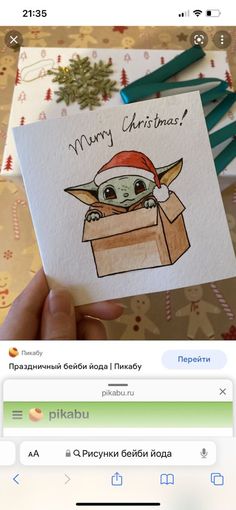 someone holding up a christmas card with an image of baby yoda in a box