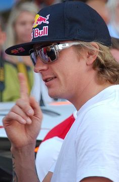 a man wearing sunglasses and a hat is giving the peace sign in front of a crowd