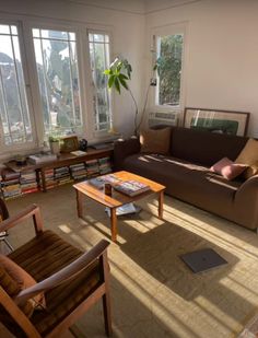 a living room filled with lots of furniture next to large windows and bookshelves