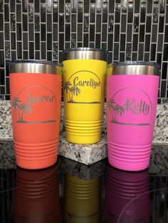 three different colored tumblers sitting on top of a black counter next to each other