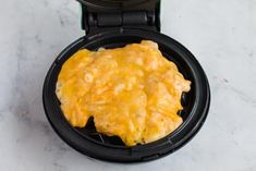 an omelet in a waffle maker on a marble countertop with a black lid