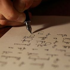 a person writing on paper with a fountain pen in their left hand and the other hand holding a pen