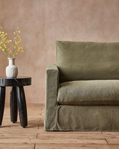 a living room with a couch, table and vase on the floor next to it