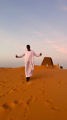 a man is walking in the desert with his arms outstretched