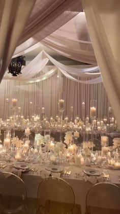 a banquet hall with tables and chairs covered in white draping, lit by candles