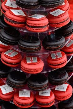 there are many red and black macaroons stacked on each other in this tower