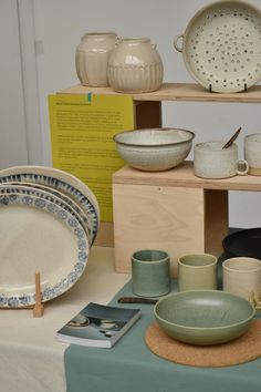 there are many plates and bowls on the display table, including one with a spoon