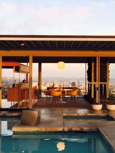 an outdoor dining area next to a swimming pool with a view of the city in the distance