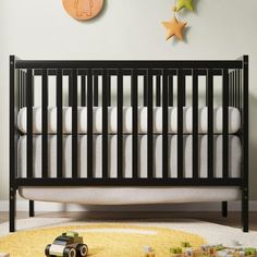 a black crib with white sheets and toys on the floor in front of it