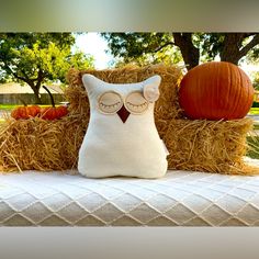 an owl pillow sitting on top of hay next to pumpkins