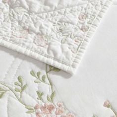 closeup of the corner of a quilted bed with flowers and leaves on it