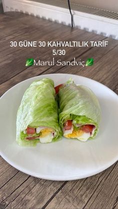 a white plate topped with two lettuce wraps