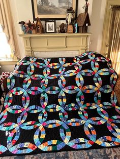 a large black quilt on top of a bed in a living room next to a fireplace