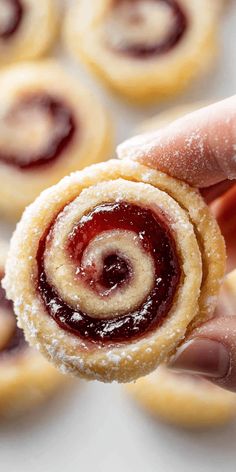 a hand holding a pastry with jelly inside