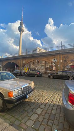 cars parked in front of a building with a television tower in the background