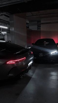 two cars parked in a parking garage with red light coming from the back lights on