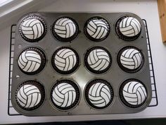 cupcakes with white and black designs in a muffin tin on a counter