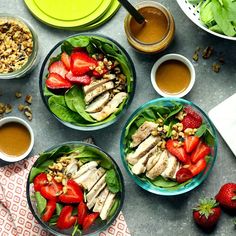 three bowls filled with salad and strawberries on top of a table