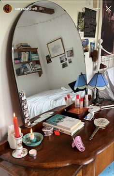 a mirror sitting on top of a wooden desk next to a lamp and book shelf