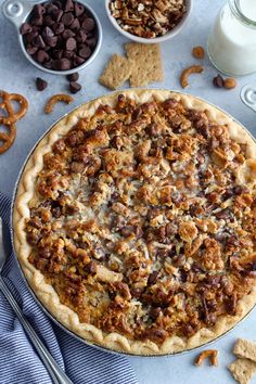 an uncooked pie sitting on top of a table next to bowls of nuts