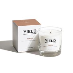 a candle sitting next to a box on a white surface with the words yield printed on it