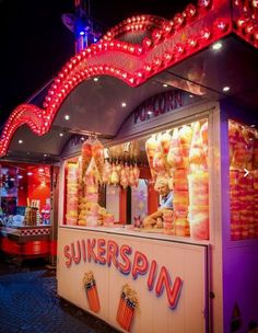 the food stand is lit up with red lights and popcorn buckets on it's sides