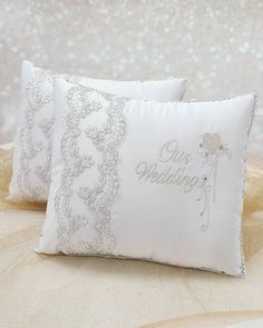 two white wedding pillows sitting on top of a bed