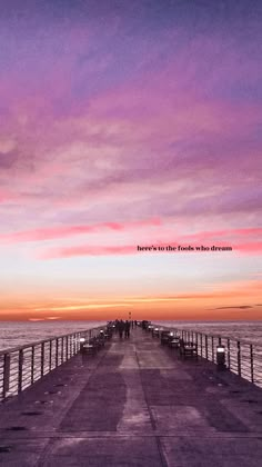 a pier with people walking on it at sunset