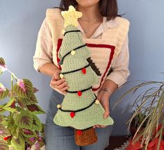 a woman is holding a crocheted christmas tree