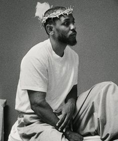 a black and white photo of a man with a crown on his head sitting on a bed