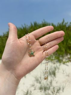 This coastal inspired necklace features a white and gold chain, and is finished with a colorful enamel starfish charm in the color of your choice. This 16 inch necklace closes using a gold lobster claw.  If you do decide to wear your jewelry to the beach, consider slipping it off and stowing it in a secure place before you head into the water. If you like this, you'll love the matching earrings! Check it out here on my shop! https://www.etsy.com/listing/1724960232/coastal-inspired-starfish-earrings-beach?click_key=8ccdb0f39da7ad646401ef427358bf5007cf2d4e%3A1724960232&click_sum=63d9e728&ref=shop_home_active_1 All orders will be packaged in a small box along with bubble packaging for safest of travels to you! Thank you for supporting my small business! - Olivia from The Sandy Poppy <3 Adjustable Green Starfish Jewelry, Adjustable Green Jewelry With Starfish Charm, Starfish Charm Necklace With Round Beads For Gifts, Adjustable Necklace With Starfish Charm, Adjustable Necklace With Starfish Charm And Round Beads, Green Starfish Charm Jewelry As Gift, Ocean-inspired Starfish Charm Beaded Necklace, Ocean-inspired Starfish Beaded Necklaces, Beaded Strand Jewelry As A Gift