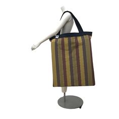 a mannequin's head is holding a striped tote bag on display