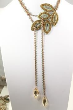 an elaborate necklace with gold and green beads on a white mannequin headdress