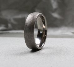 a wedding ring is shown sitting on a table with a gray cloth in the background