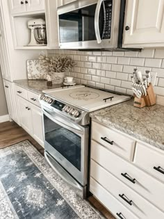 a stove top oven sitting inside of a kitchen next to white cabinets and counter tops