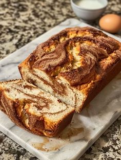 a loaf of cinnamon swirl bread sitting on top of a white plate next to an egg