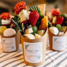 small cups filled with assorted fruits and cheeses on top of a table cloth